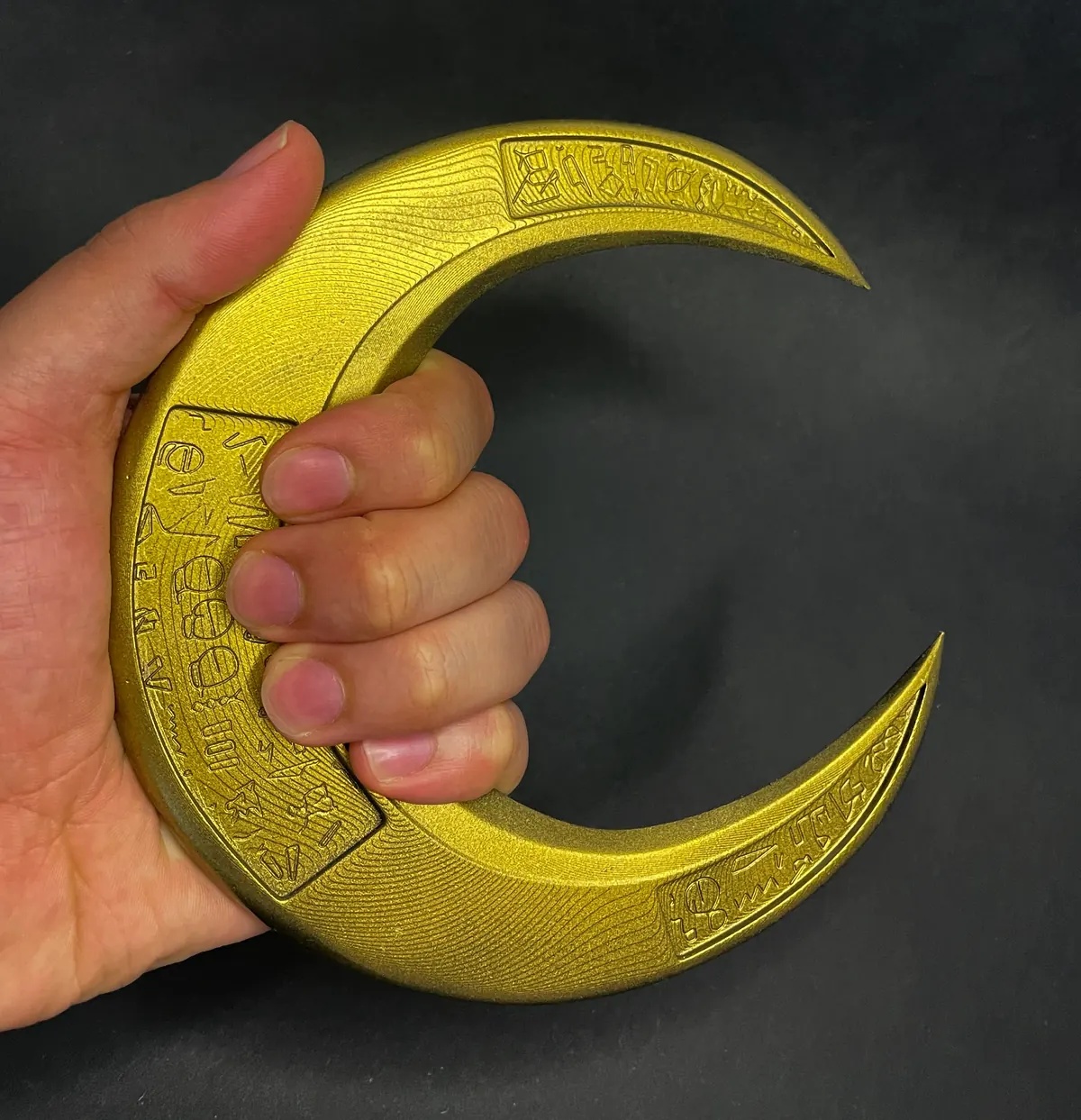 Goldener Halbmond mit Gravur in der Hand
