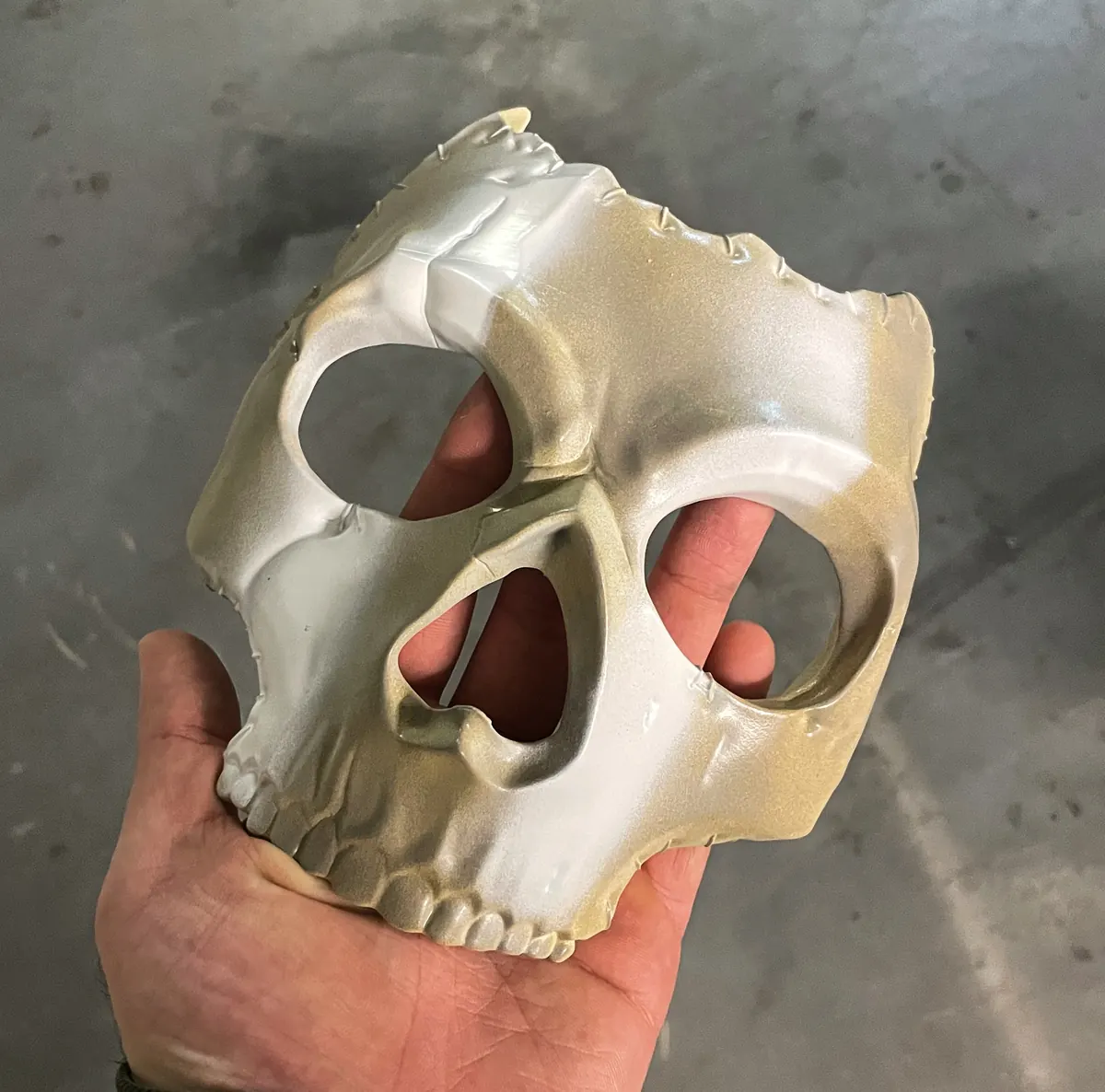 Weiße Totenkopf-Halbmaske in der Hand
